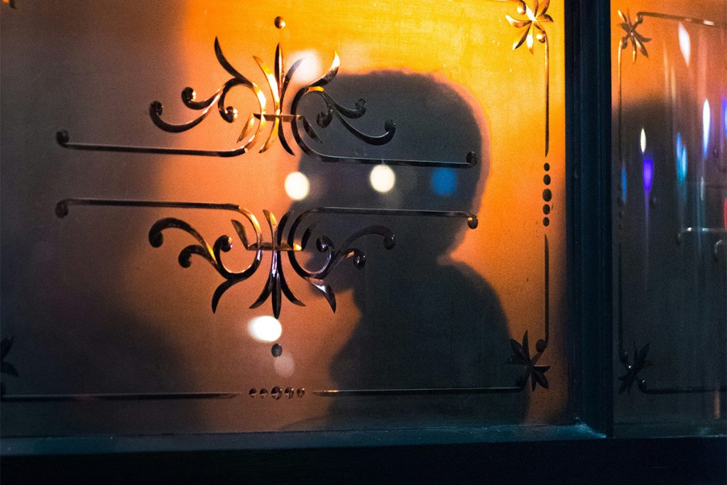 silhouette of a person backlit through a bar or restaurant's frosted window