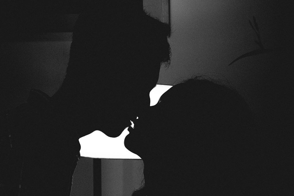 man and woman kissing silhouetted in a dark room